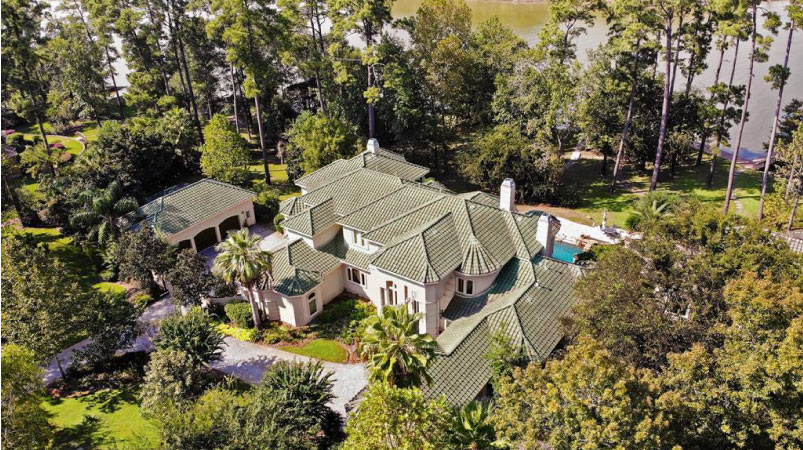 Aerial view of a large waterfront home nestled among the trees in Kingwood, Texas. 