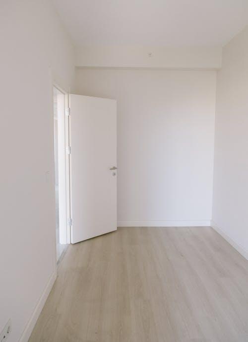Free An Empty Room with White Wall and Wooden Floor  Stock Photo