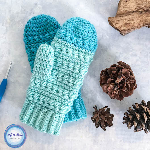 blue mittens on white background with hook and pinecones