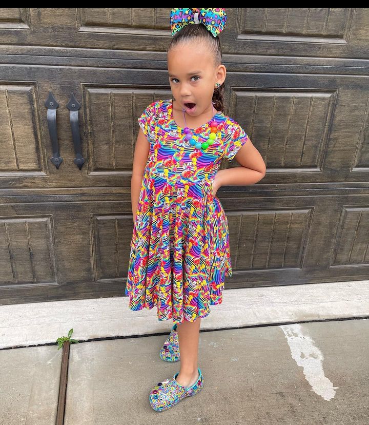 A beautiful young girl with colorful floral prints and patterns while rocking her crocs.