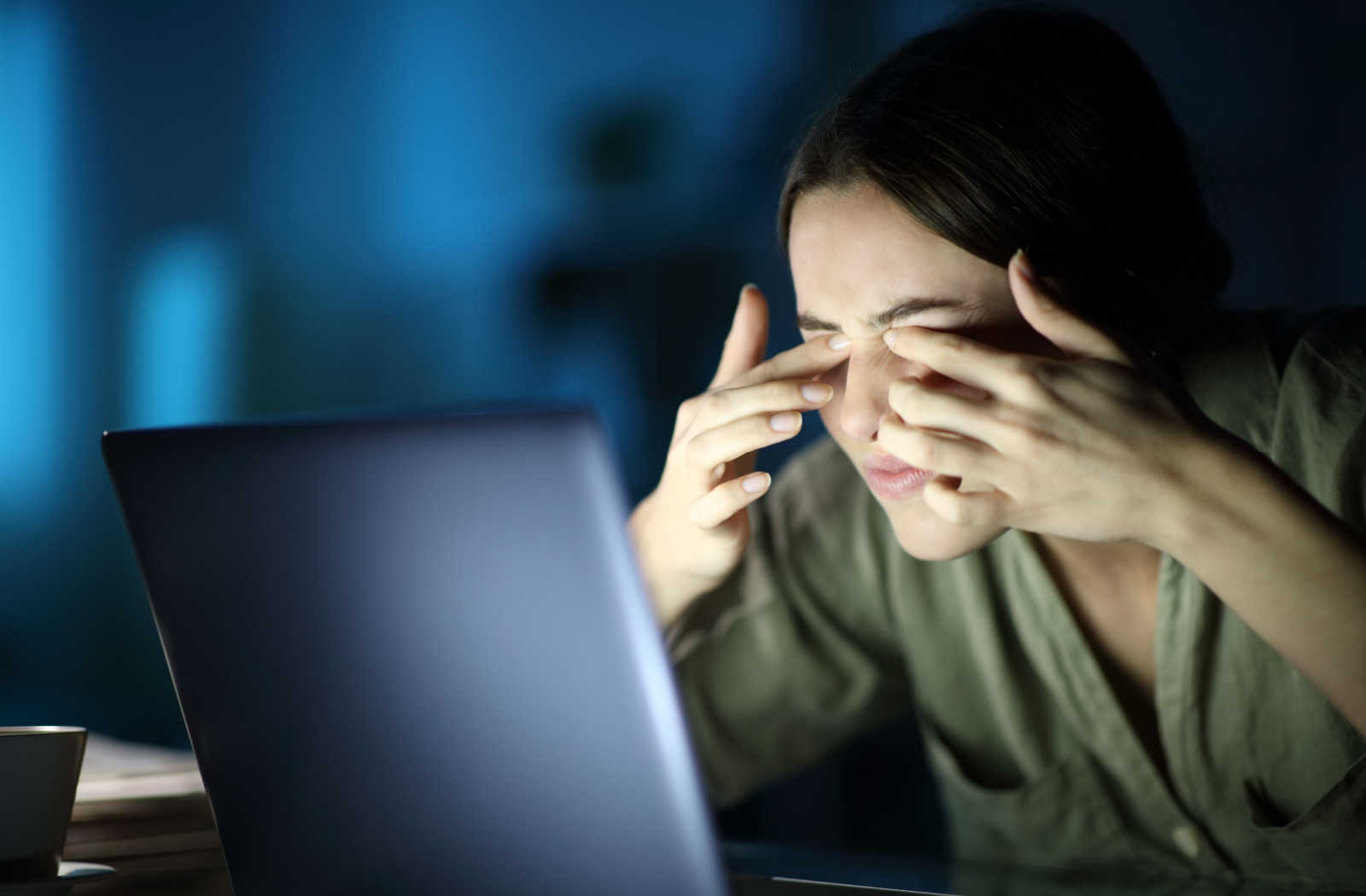A woman with her hands on her eyes because she feels the effects of computer vision syndrome playing video games on her laptop