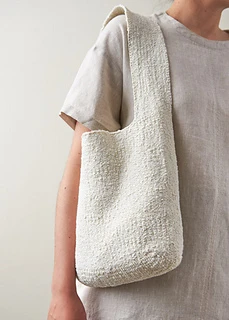 woman carrying white knit tote bag
