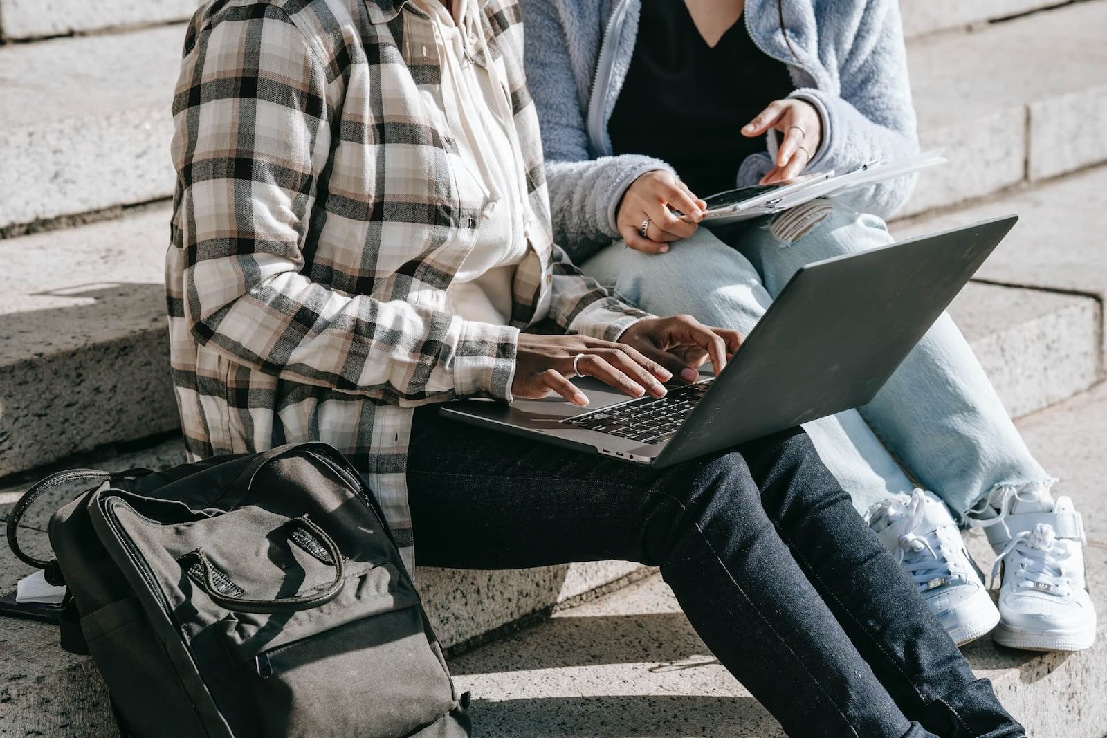 College students sitting on steps outside with a laptop