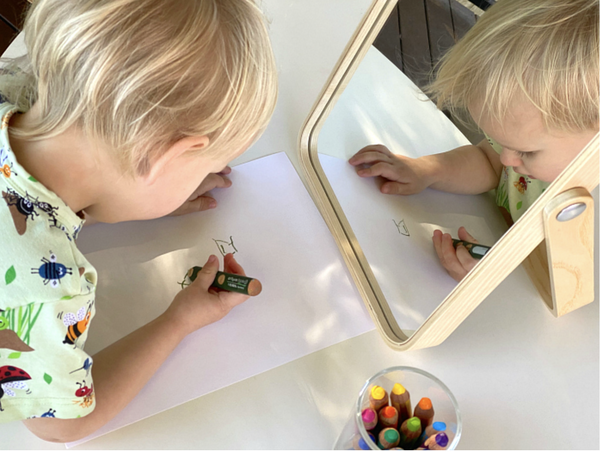 Child drawing a self portrait using a mirror