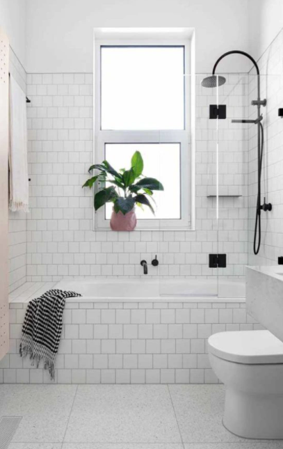 Banheiro com banheira embutida revestida de azulejo subway tiles branco e parede do box também, piso cerâmica branco, chuveiro, torneira e demais acessórios pretos