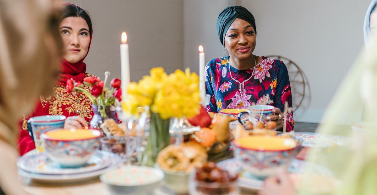 النساء المسلمات السعيدات في عيد الفطر يجلسن على المائدة مع وجبات لذيذة قبل أن يحتفلن بنهاية فترة الصيام في رمضان