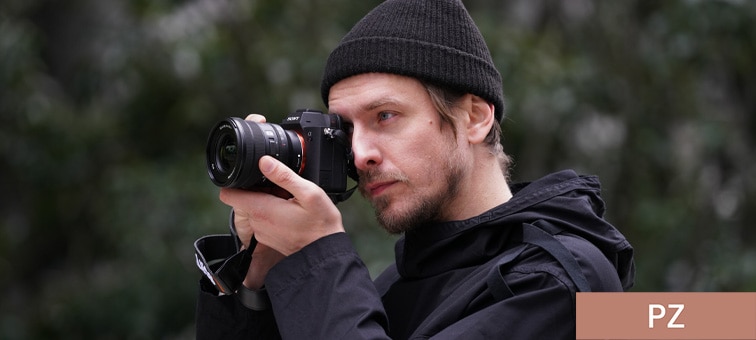 Image of a man holding a camera (ILCE-7M4) with the SELP1635G lens attached