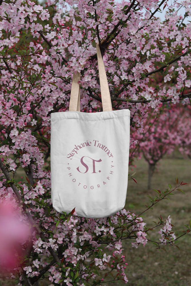 An example of Stephanie's logo being used on a tote bag hanging in cherry blossoms.