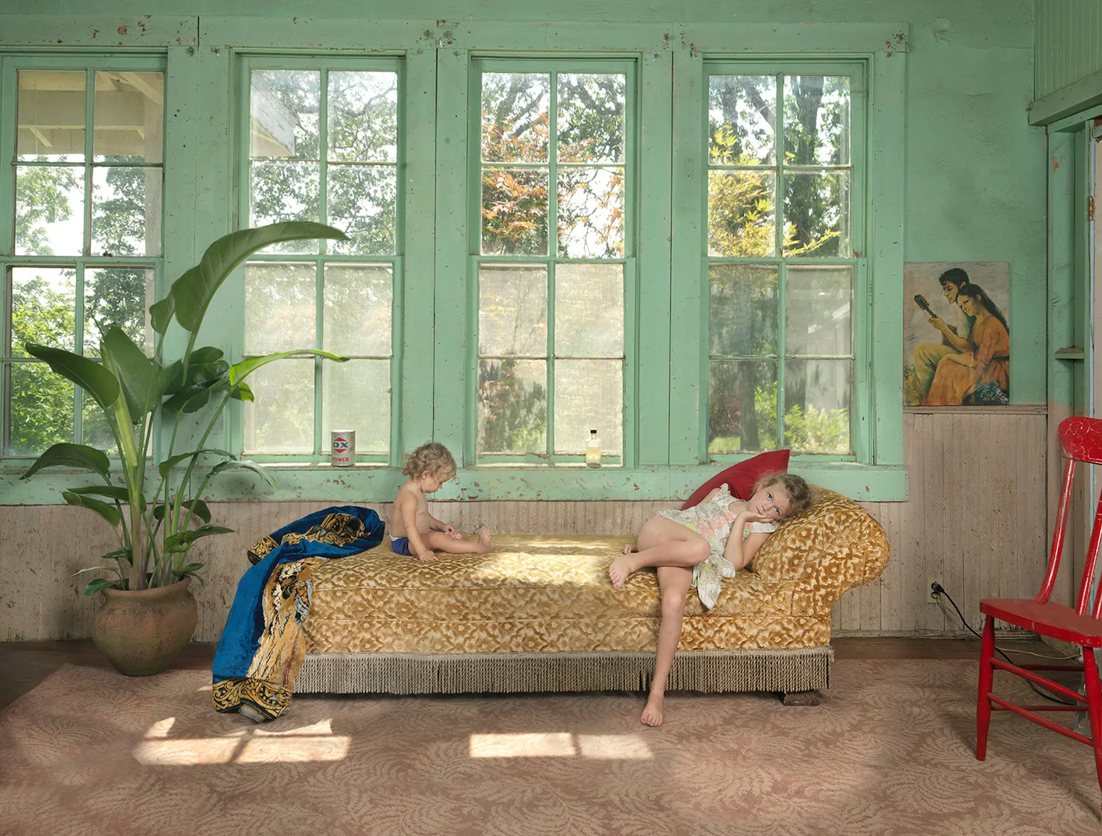 Photo of two young children lying on a chaise longue. 
