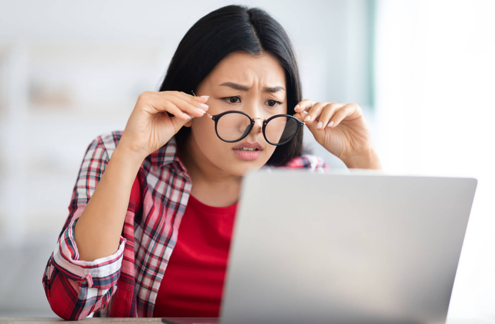 a woman looks over her glasses at her computer due to her prescription changing