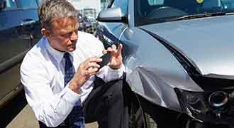 A Massachusetts car accident lawyer takes photos of a damaged vehicle after an accident.