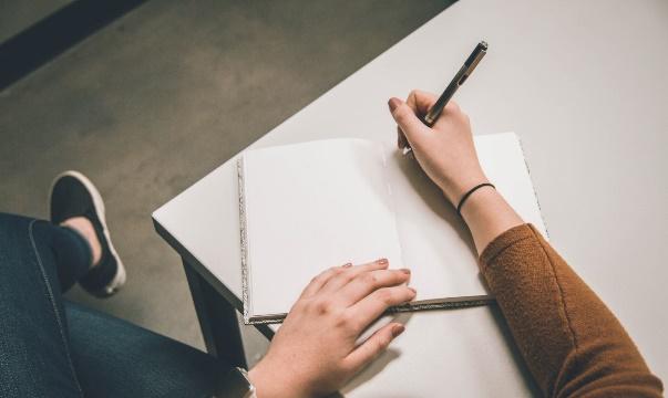 A person writing on a piece of paper

Description automatically generated with medium confidence