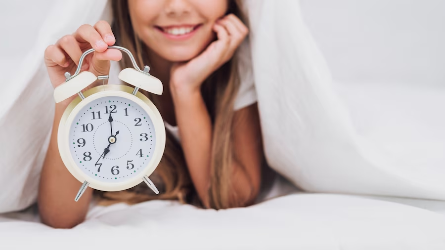 Happy student holding a white clock, illustrating the flexible morning routine in homeschooling.