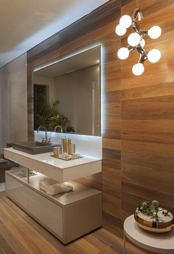 32 Inspirações de banheiros com porcelanato amadeirado - banheiro com parede e piso com revestimento amadeirado, armário branco e espelho grande.