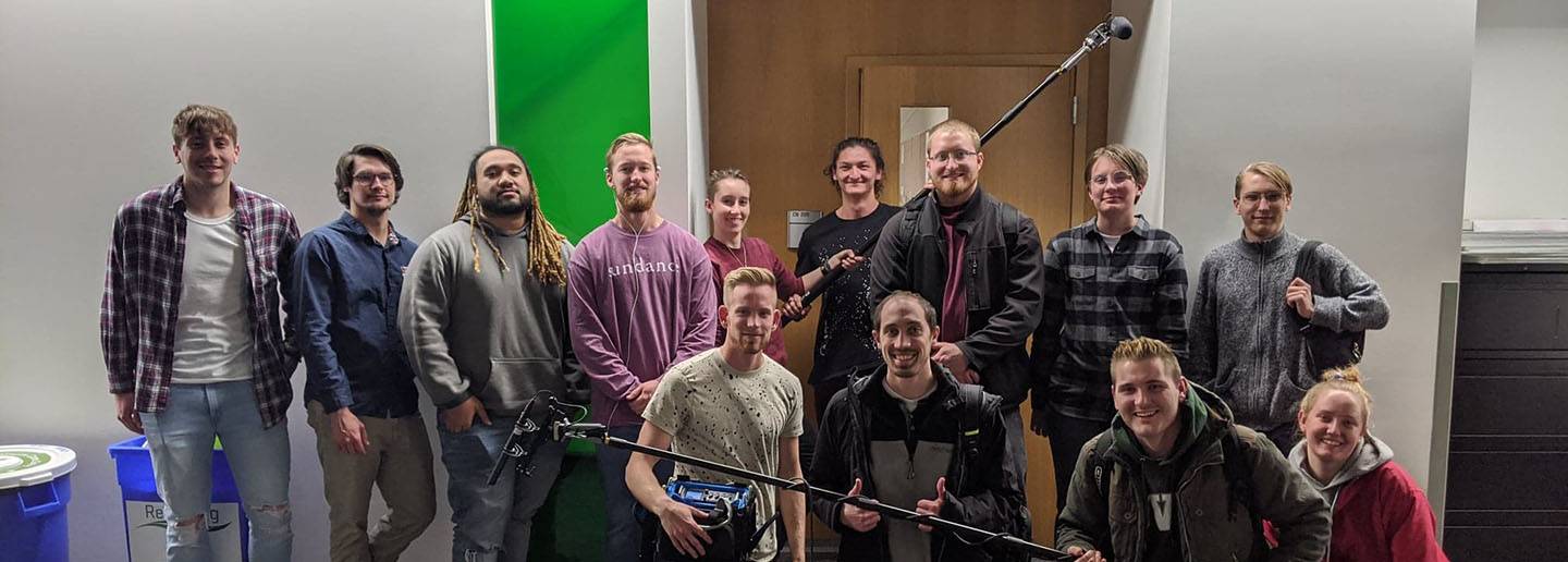 Audio club members on campus with boom poles, microphones, and audio mixer