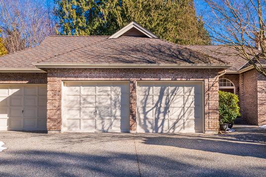 WeServe | two garages with white doors in front of gravel paved driveway with a brown roof 