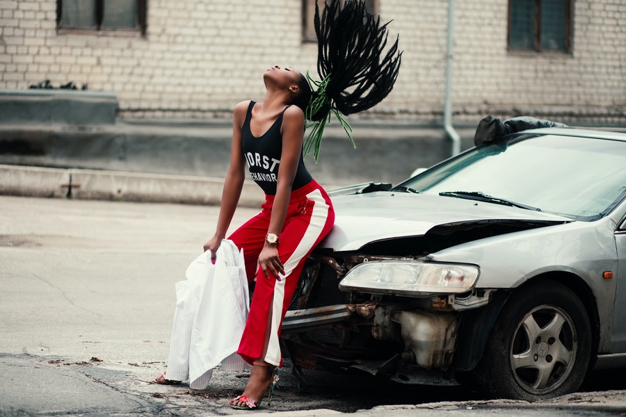 Dama negra sentada en un automóvil con pantalones de chándal