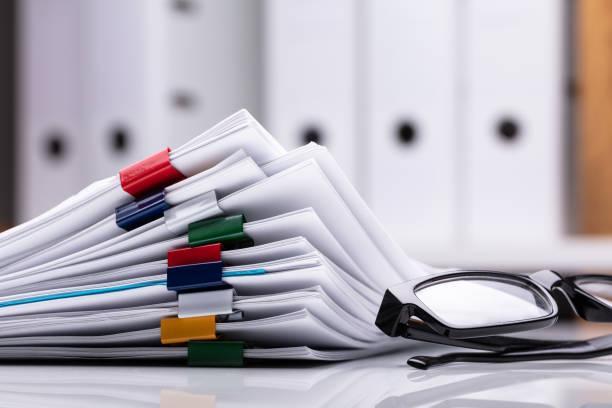 Stacked Documents And Eyeglasses Stacked Documents With Colorful Paperclips And Eyeglasses tax folders stock pictures, royalty-free photos & images