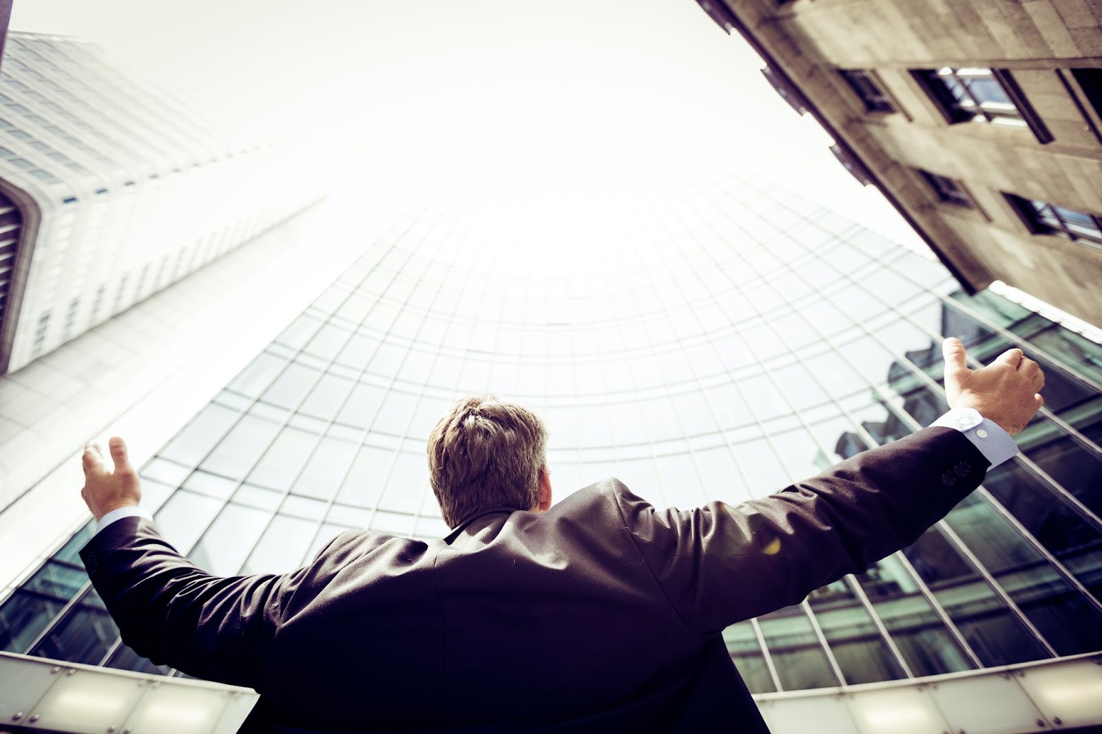 a man in the middle of buildings with his arms raised to his sides