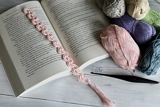 light pink bookmark on open book with yarn skeins 