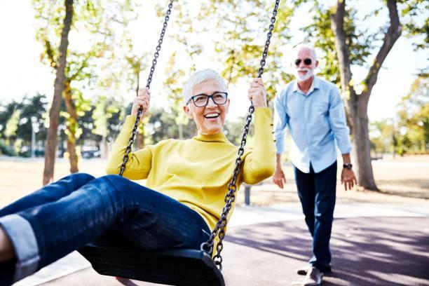 senior couple happy swing park love active senior couple enjoying  a swing in park couple outdoor games stock pictures, royalty-free photos & images