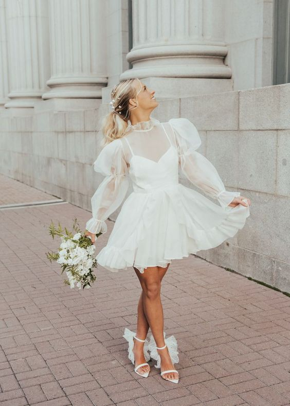 a bride in a short flared wedding dress holding a flower