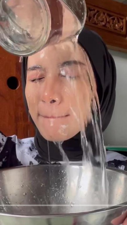 A snapshot of a social media post showing a woman pouring water over her face
