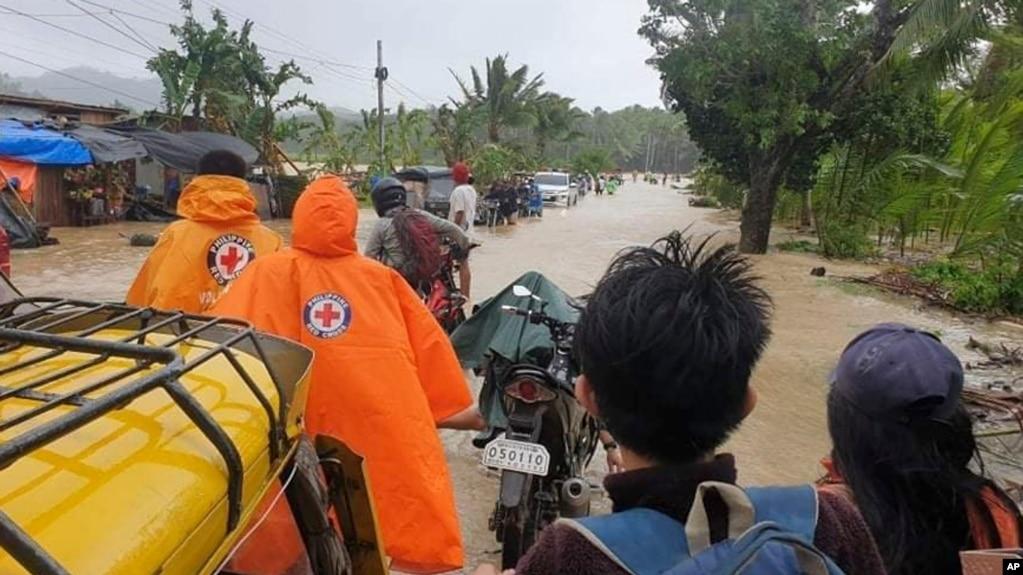 Người dân Philippines đi qua một đoạn đường ngập lụt do bão gây ra. 