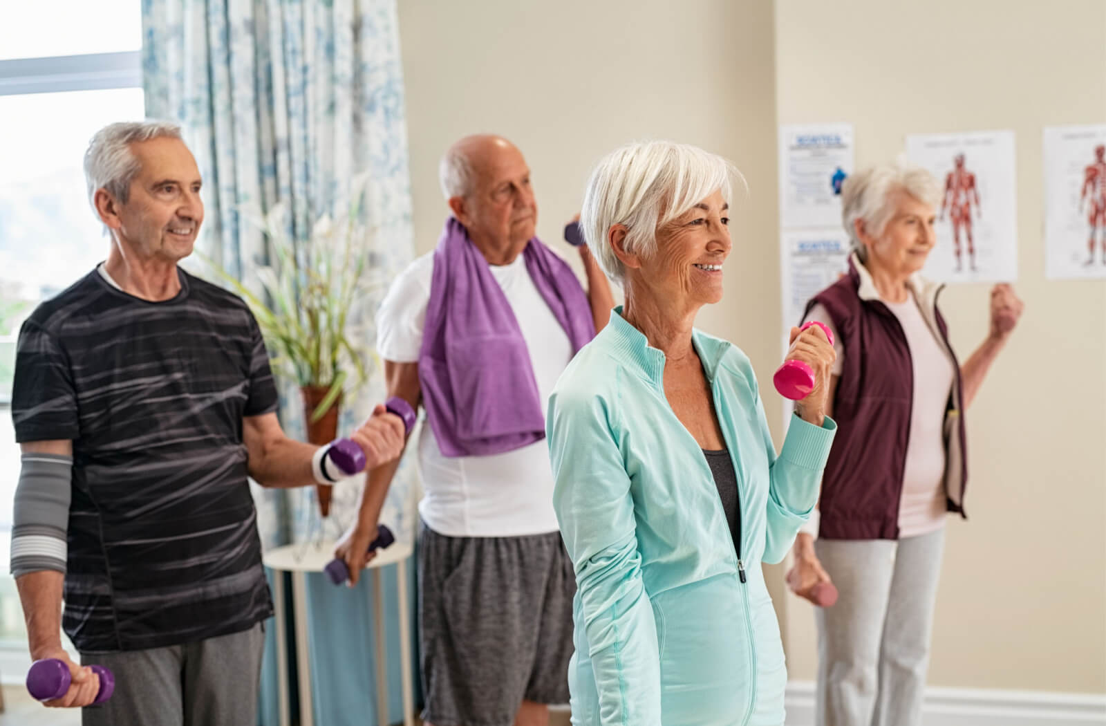 A group of active seniors exercising with dumbbells at the gym in an assisted living community.