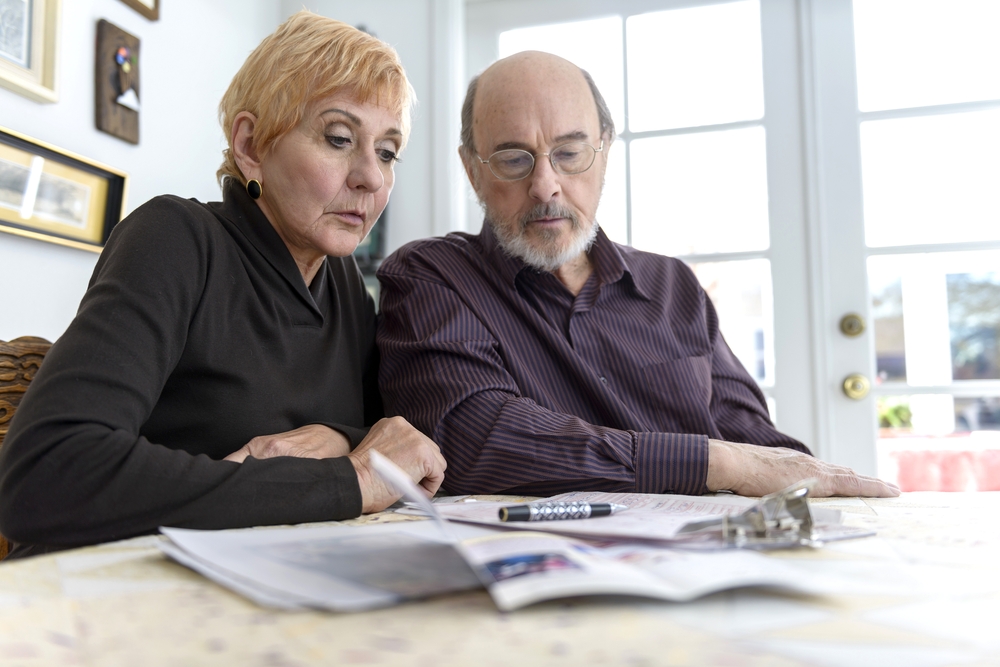 Senior couple examine paperwork in attorney's office.