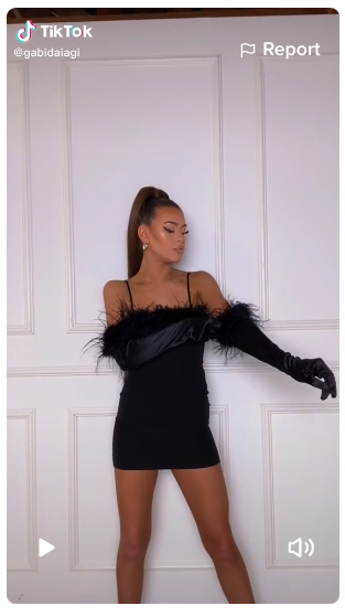 screenshot of a lady wearing a short black dress with feather trims in a TikTok video