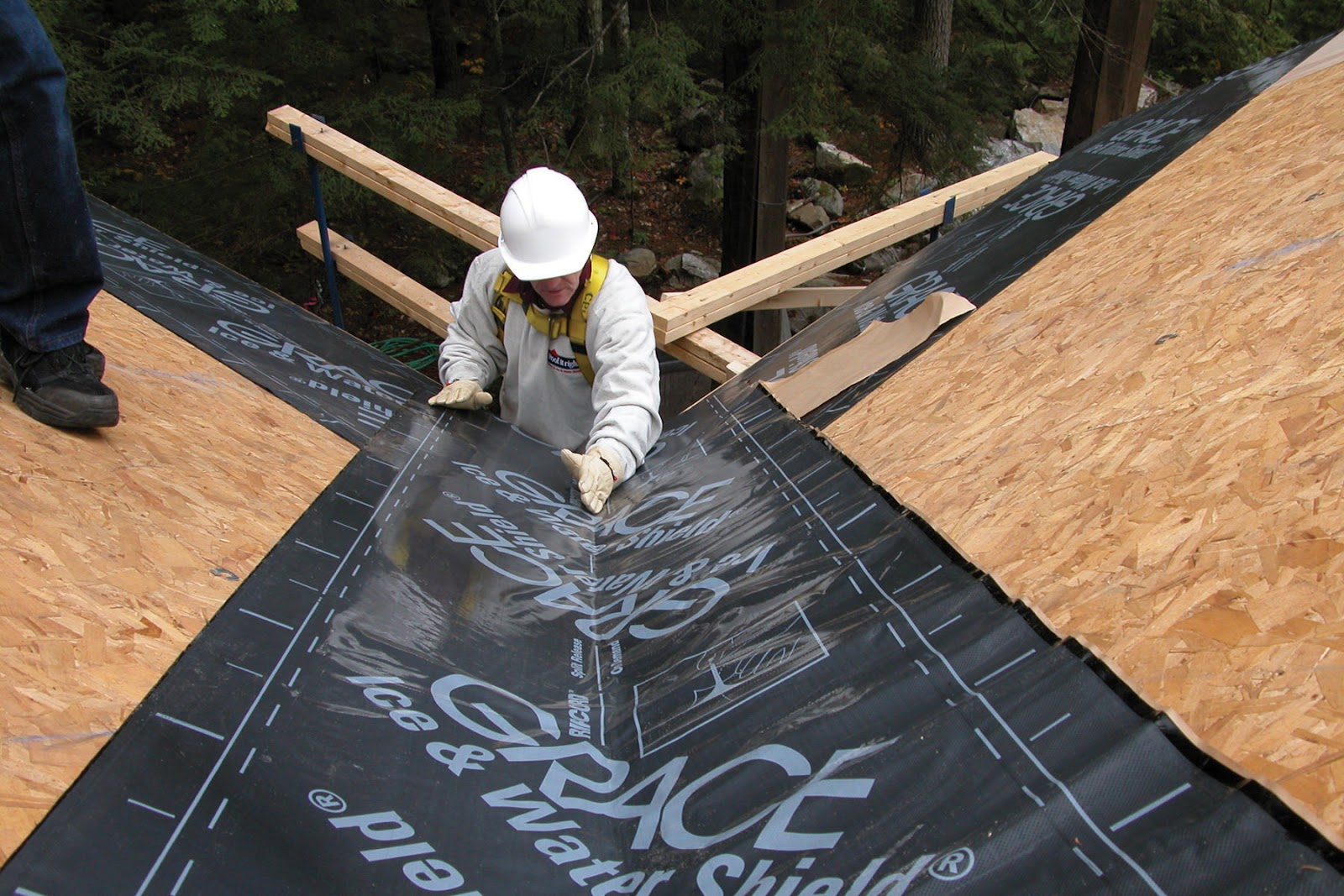 Roofing contractor laying underlayment down during a roof replacement.