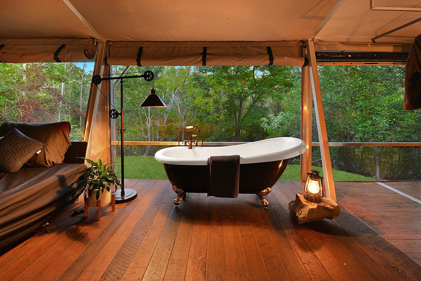 a freestanding bath in a luxe canvas tent, with the outdoors visible from behind mesh