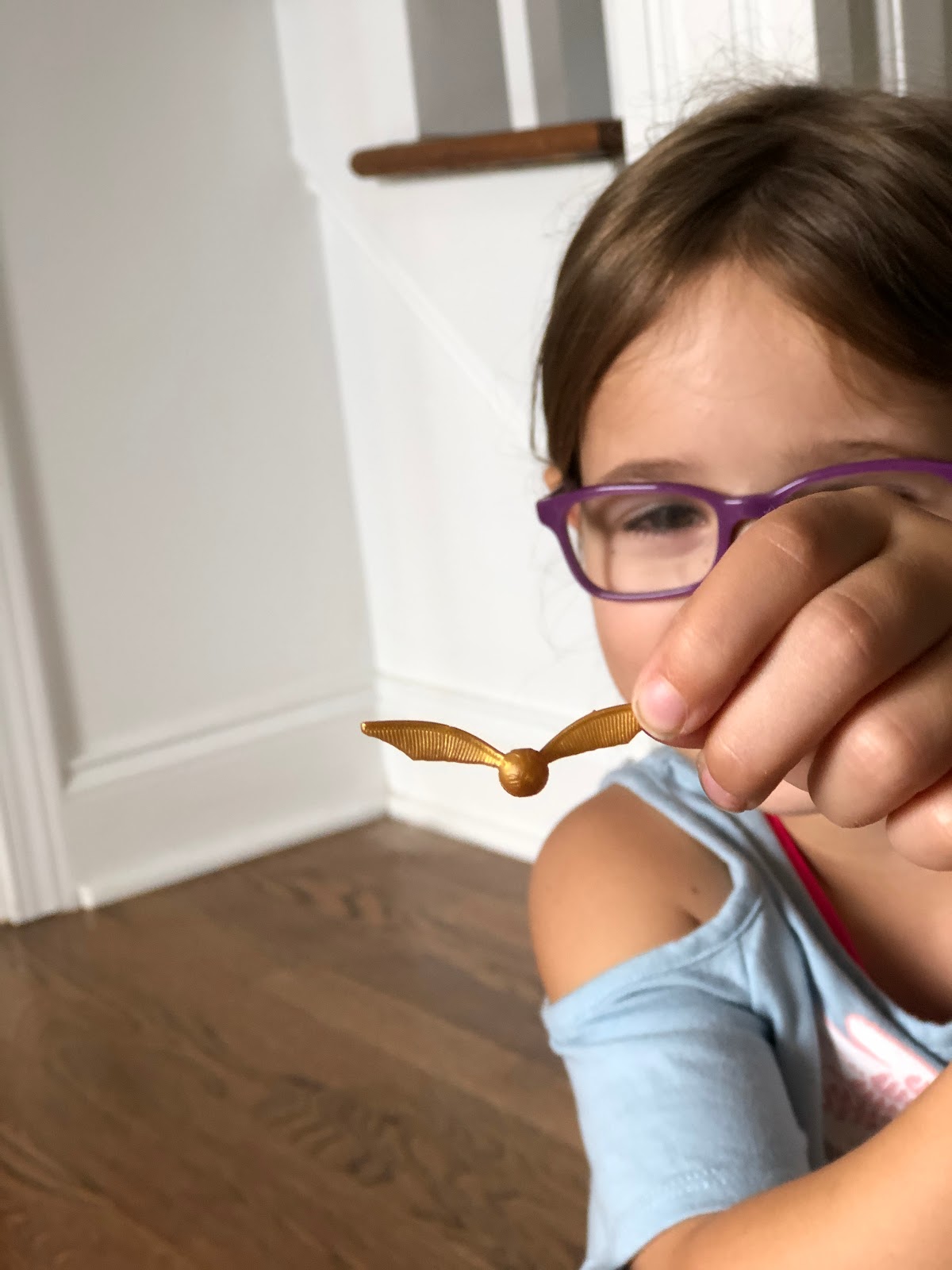 A girl little in glasses playing with a Harry Potter toy.