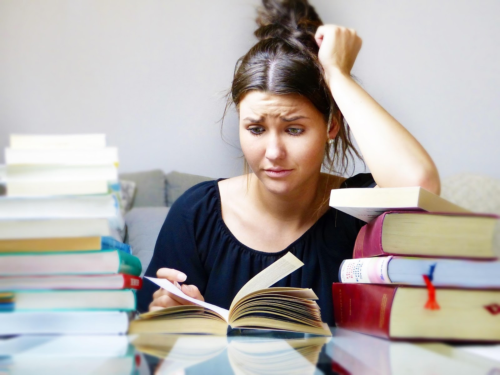 Young woman studying with piles of books around her.