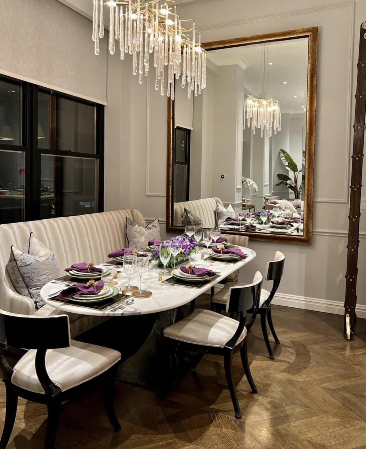 A dramatic oversized mirror adds scale to this dining room designed by Luis Enrique Design.