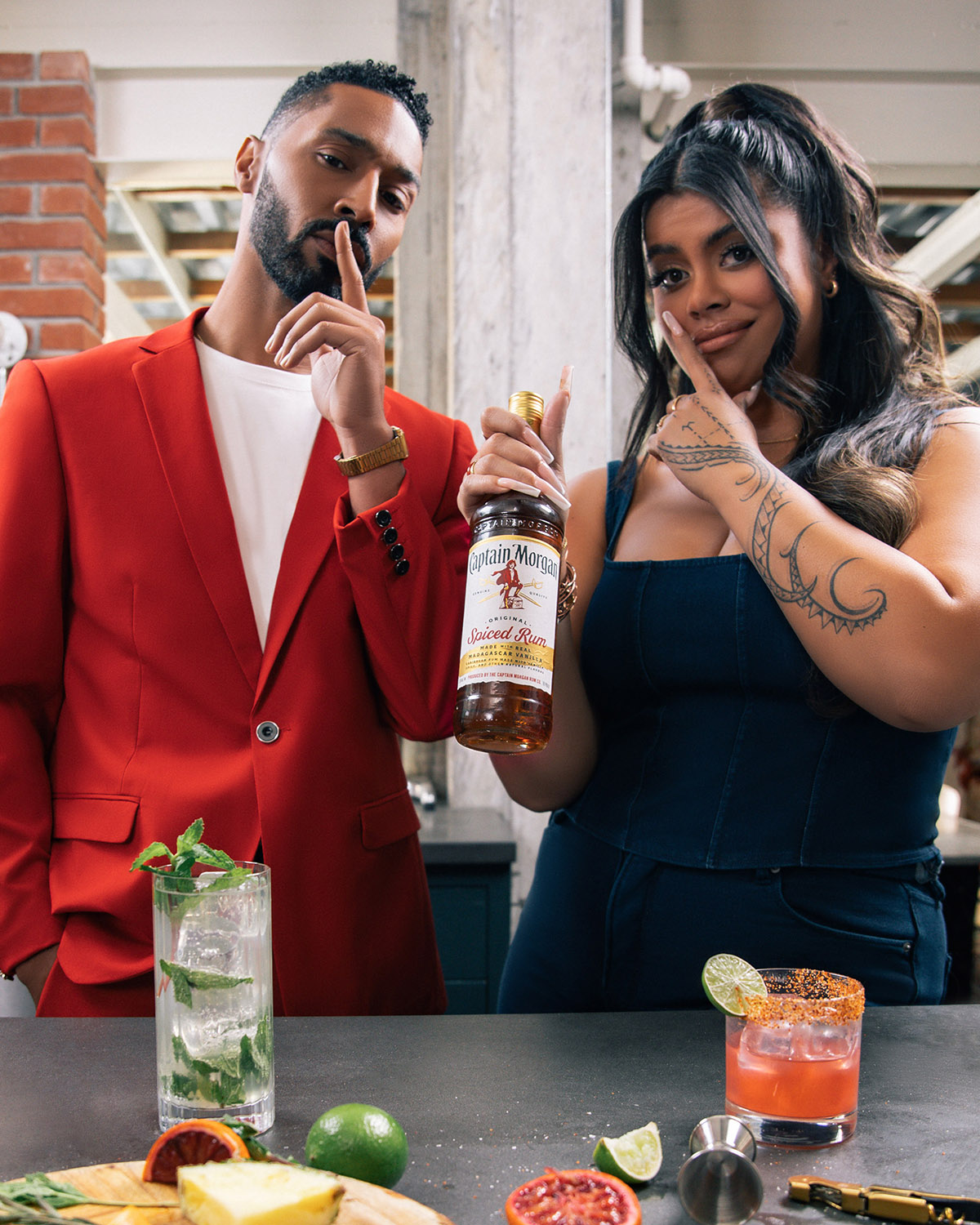 A girl stands next to a man and holds a bottle of alcohol