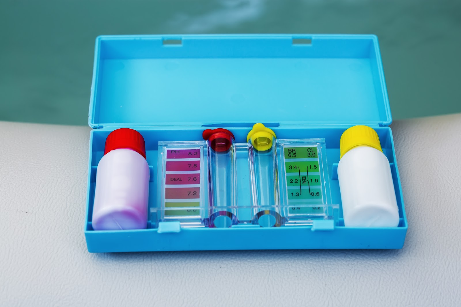 a pool test kit with yellow and pink colored solution and two test tubes inside of a blue box 