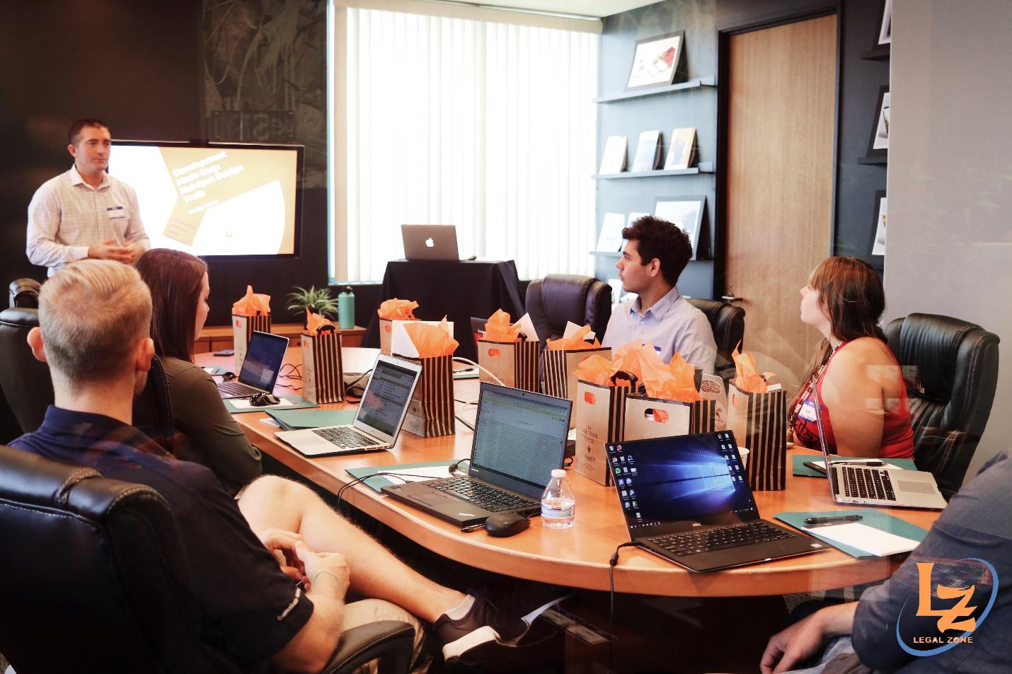 A group of people sitting around a table with laptops

Description automatically generated with medium confidence