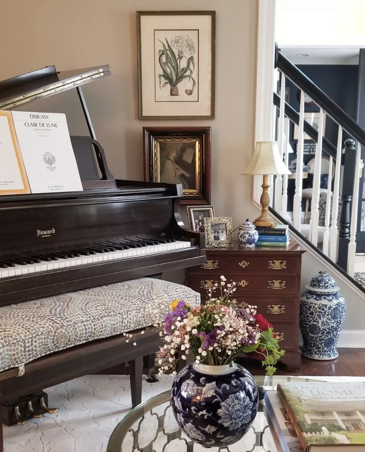 This beautiful music room features a Howard baby grand piano which is surrounded by classic chinoiserie elements including blue and white urns and a fun, modern mosaic patterned cushion on the long piano bench.
