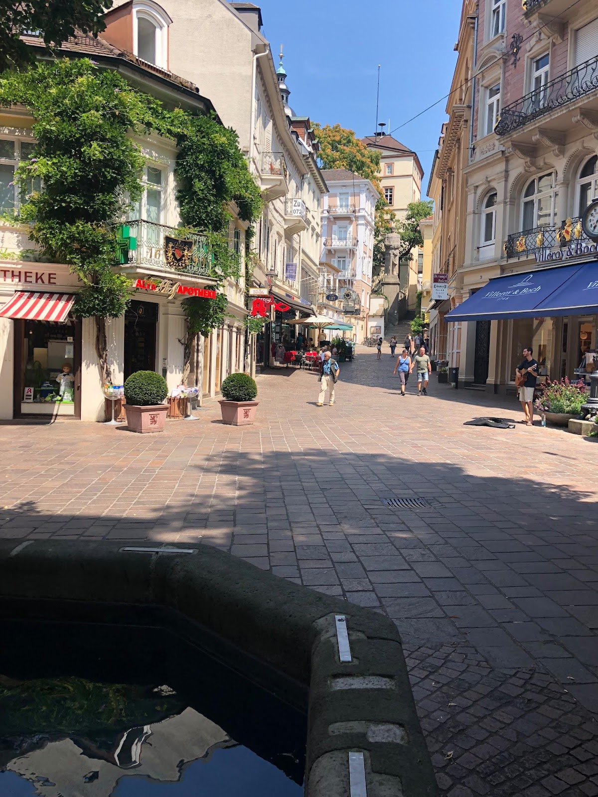 baden baden walking street colorful bright storefronts and restaurants street performer playing the guitar on a clear sunny day in germany