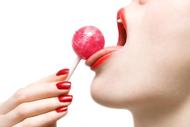 Woman licking sweet sugar candy closeup