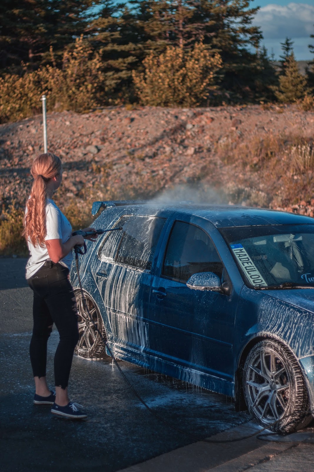 Woman washing her car to avoid some of the common mistakes when washing your car