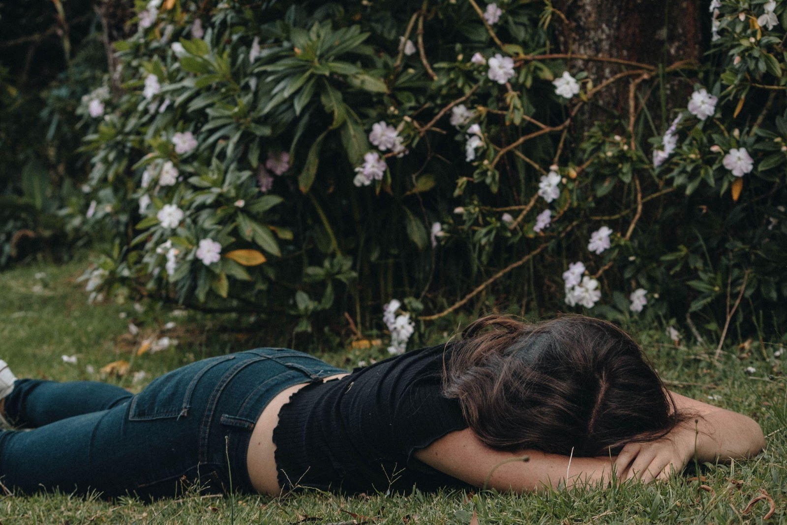 Femme fatiguée allongée dans l'herbe la tête entre les bras.