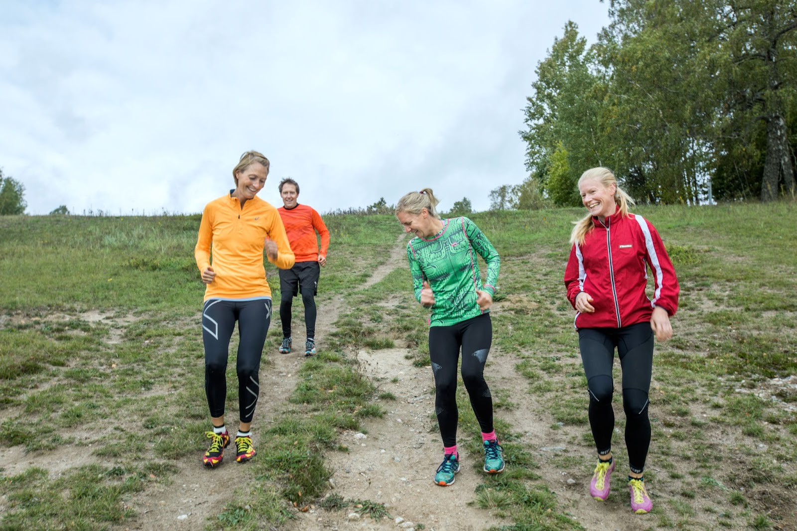 fyra personer springer ner för en backe och är glada