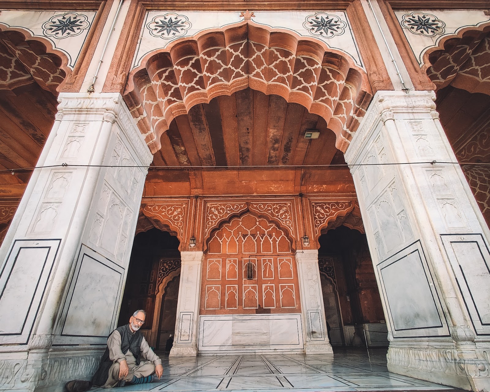 Photograph of a man sitting inside Jama Masjida