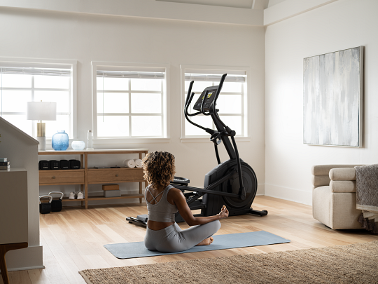 Woman Practicing Yoga Next to Her NordicTrack Elliptical