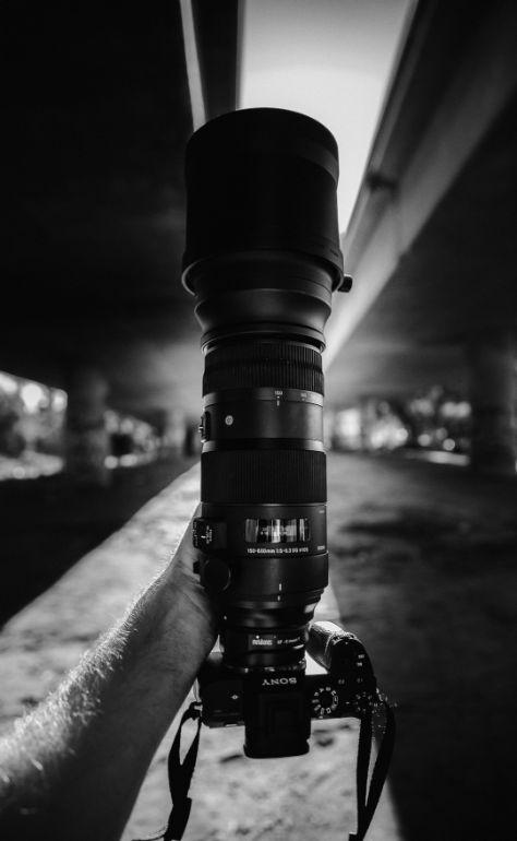 Homen segundo uma camera sony com lente longa