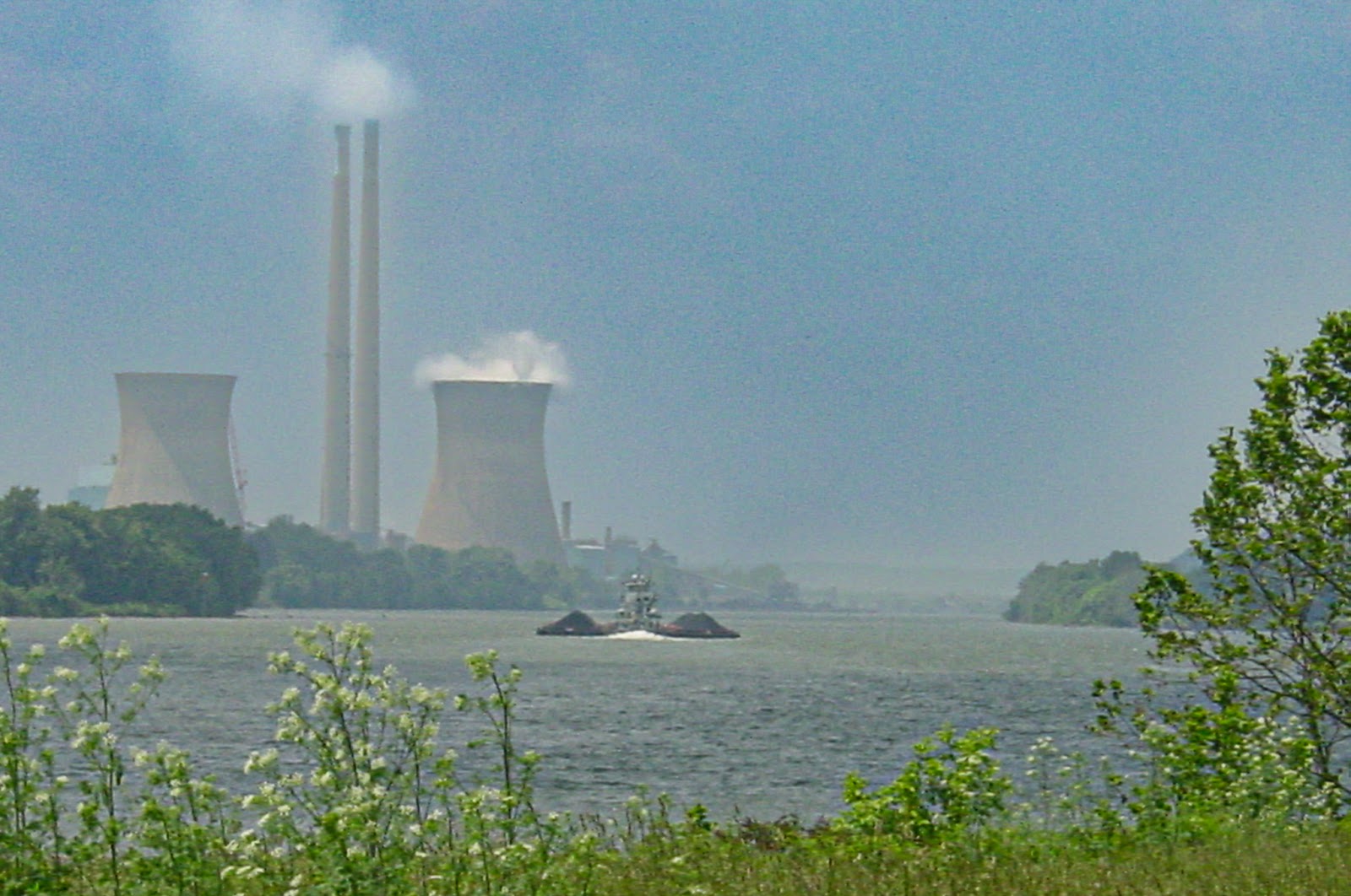 Two tall chimneys and two nuclear cooling towers beside a river. 