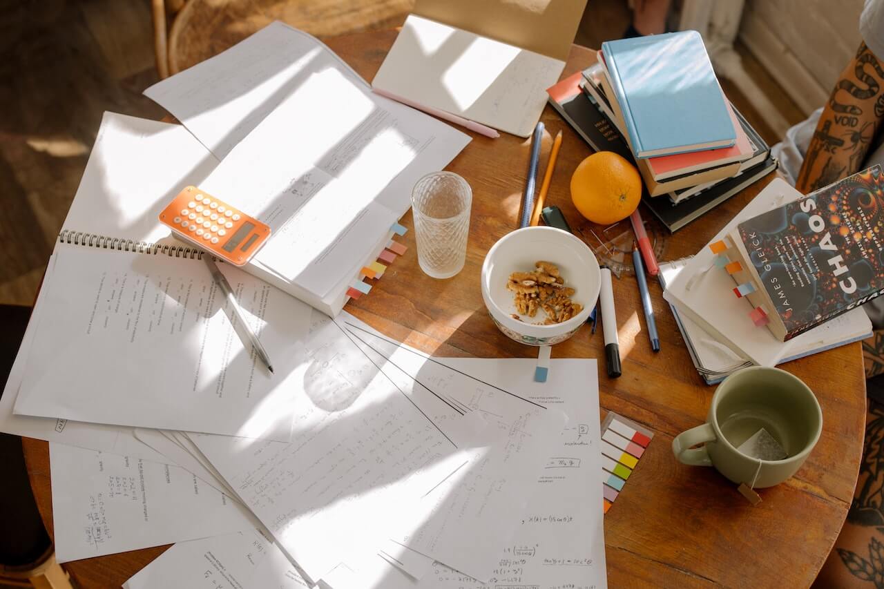 Notebooks, text books, calculators, and other study materials spread out on a table
